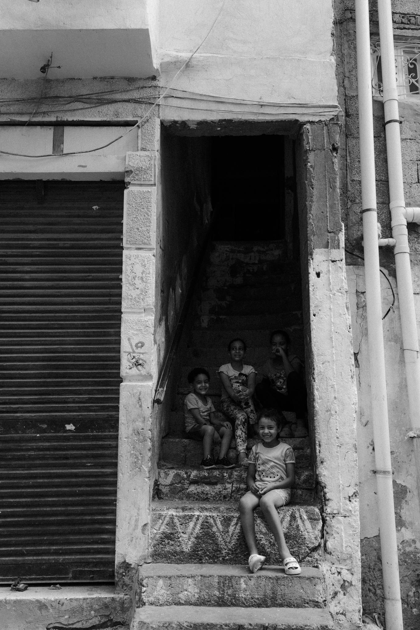 Black and white photo of children sitting on outdoor stairs in Alexandria, Egypt.